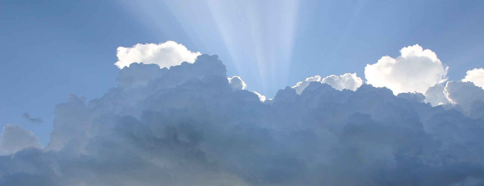 Sonnenstrahlen hinter Wolken hervorstrahlend als Symbol für Christi Himmelfahrt