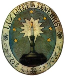 Ein Emblem mit einer brennenden Kerze, umgeben von Sternen, und dem lateinischen Text „LUX LUCET IN TENEBRIS“ oben, Dabei handelt es sich um das Waldenser-Wappen.